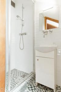 a white bathroom with a shower and a sink at Pokoje Gościnne Cheval in Krakow