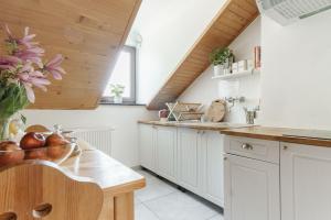 a kitchen with white cabinets and a wooden ceiling at Pokoje Gościnne Cheval in Krakow
