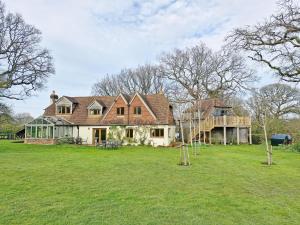 una casa grande en un campo con árboles en Broomy Cottage en Pulborough