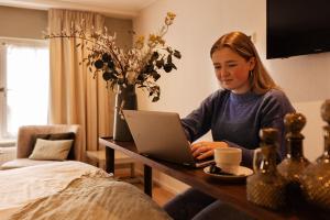 une femme assise à une table avec un ordinateur portable dans l'établissement Boutique Hotel Elburg met Tapperij, à Elburg