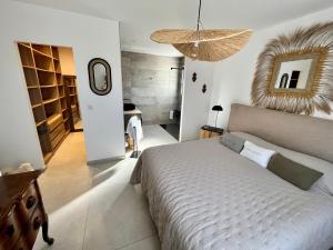 een slaapkamer met een groot bed en een kroonluchter bij jolie maison neuve au coeur des vignes in Cogolin