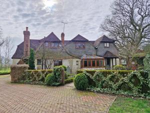 een groot huis met een stenen oprit ervoor bij Broomy Cottage in Pulborough