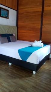 a large bed in a room with wooden walls at Naca Homestay in Manado