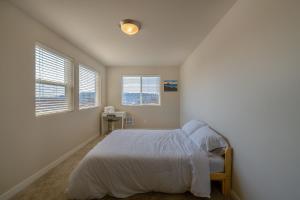 um quarto com uma cama com lençóis brancos e janelas em Seattle Urban Village -Private Room- Vashon - Roof Top View Deck em Seattle
