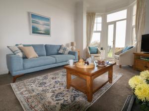 a living room with a blue couch and a coffee table at Blue Yonder in Weymouth