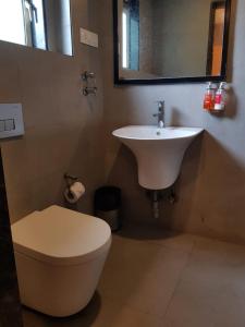 a bathroom with a sink and a toilet and a mirror at Hotel Samrat, Mumbai in Mumbai