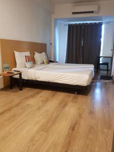 a large bed in a room with a wooden floor at Hotel Samrat, Mumbai in Mumbai