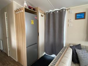a sliding door in a room with a couch at Comfy Cosy Caravan_Romney Sands in Littlestone-on-Sea