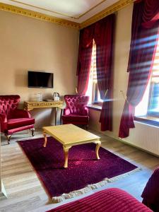 Hotel Katerina Sarayı 1877 في كارس: غرفة معيشة مع كراسي حمراء وطاولة قهوة