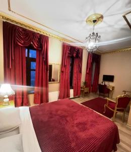 a bedroom with a large bed with red curtains at Hotel Katerina Sarayı 1877 in Kars
