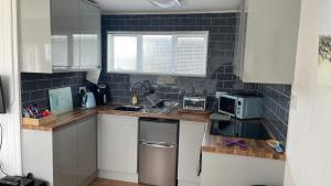 a small kitchen with white cabinets and black tiles at 25. Valencia in Selsey