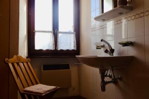 ein Badezimmer mit einem Waschbecken, einem Stuhl und einem Fenster in der Unterkunft Antica Osteria Dazio in Fusio