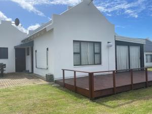a white house with a wooden deck in the yard at Sea view cottage in Great Brak River