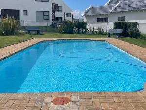 a large blue swimming pool in front of a house at Sea view cottage in Great Brak River