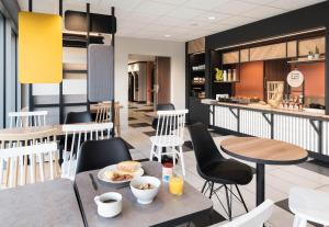 ラヴァルにあるB&B HOTEL Laval Ouestのテーブルと椅子のあるレストラン、朝食ルームを提供しています。