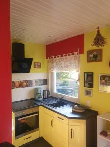 una cocina con paredes amarillas y rojas y fregadero en Gästehaus Anita, en Britten