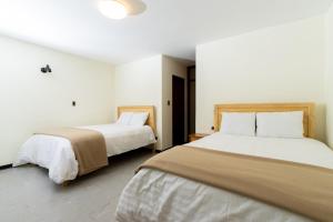 2 camas en una habitación con paredes blancas en Hotel Cipriani, en Tarma