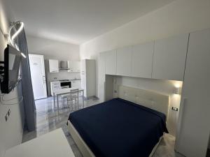 1 dormitorio con 1 cama azul y cocina en ALG Apartments con Parcheggio en Porto Cesareo
