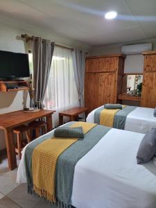 a hotel room with two beds and a television at Fraai Maraai Self Catering Apartments in Groblersdal