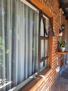 a window with curtains on a brick wall at Fraai Maraai Self Catering Apartments in Groblersdal