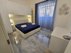 1 dormitorio con cama con sábanas azules y ventana en ALG Apartments con Parcheggio en Porto Cesareo