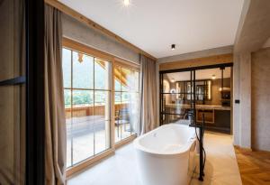 Una bañera en un baño con una ventana grande. en NOVA Moments Boutique Hotel, en Pertisau