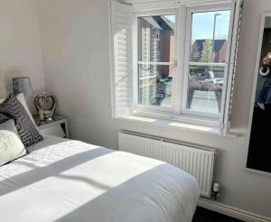 a bedroom with a white bed and a window at Cathedral Coach House in Lichfield