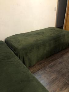 twee groene bedden op de vloer in een kamer bij La Chiquitita in Villa Dolores