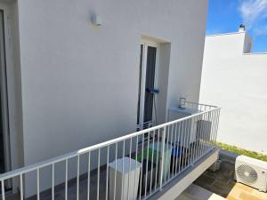 balcón de un edificio blanco con barandilla blanca en ALG Apartments con Parcheggio en Porto Cesareo