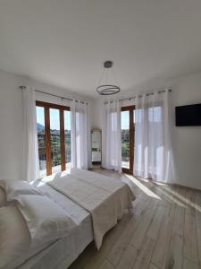 a white bedroom with a large bed and large windows at Villa Mafalda in Pietra Ligure