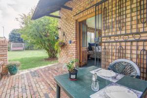 a green table and chairs on a patio at Woodpecker Bachelor Cottage in Boksburg
