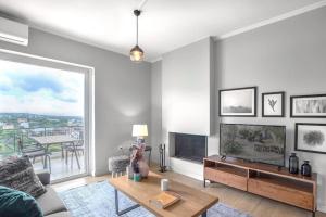 Una sala de estar con un sofá y un televisor. en Tranquil Modern Ηaven, en Atenas