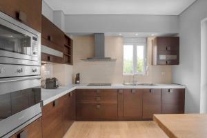 Una cocina grande con gabinetes de madera y fregadero. en Tranquil Modern Ηaven, en Atenas