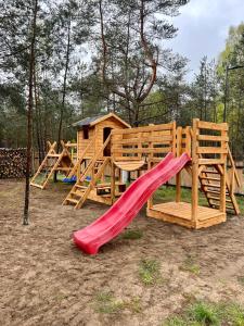 a wooden playground with a slide and a house at BORSKÓWKA domki z balią z jacuzzi in Borsk