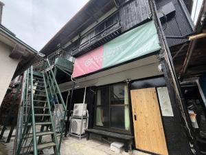 een gebouw met een bord aan de zijkant bij 温泉街の入り口にあるゲストハウス SLOW HOUSE yugawara in Yugawara