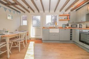 a kitchen with gray cabinets and a table with a tableablish at Quaint 2 bed cottage near North Norfolk Coast - Harpers Cottages in Syderstone
