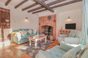 a living room with a couch and a fireplace at Quaint 2 bed cottage near North Norfolk Coast - Harpers Cottages in Syderstone