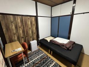 Habitación pequeña con cama pequeña y escritorio. en 温泉街の入り口にあるゲストハウス SLOW HOUSE yugawara, en Yugawara