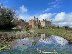 an old castle with a pond in front of it at Apartment at Llanerchydol Hall in Welshpool