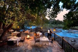 a man standing in front of a restaurant next to a river at INYAMATANE LUXURY LODGES at Kruger Park Lodge in Hazyview
