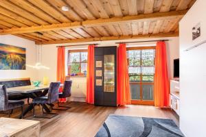 ein Esszimmer mit orangefarbenen Vorhängen und einem Tisch in der Unterkunft Komfortwohnung mit Pool und Sauna in Hauzenberg