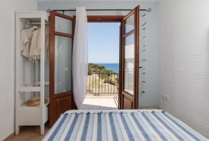 een slaapkamer met een deur naar een balkon bij Apiliotis sunrise beach villa in Ligaridia