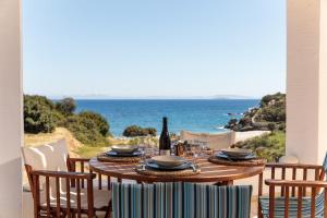 una mesa con una botella de vino y sillas en el patio en Apiliotis sunrise beach villa, en Ligaridia