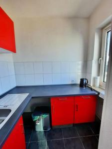 a small kitchen with red cabinets and a sink at City-Wohnung mit Ausblick in Bochum