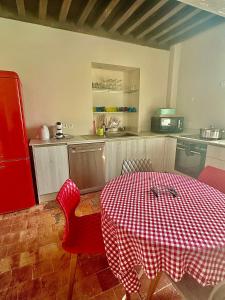 a kitchen with a table with a red and white checkered table cloth at L'Ancien Moulin du Château de Marrault - Gîte de groupe in Magny