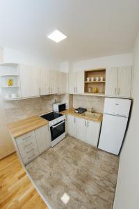 an empty kitchen with white appliances and wooden floors at Vojvodjanska zora - besplatan parking in Sombor