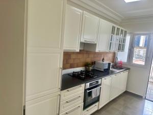 a kitchen with white cabinets and a stove top oven at SCI H in Douala