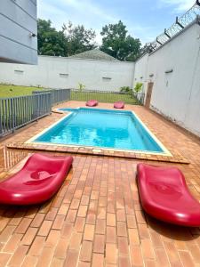 a swimming pool with two red chairs on a brick patio at SCI H in Douala