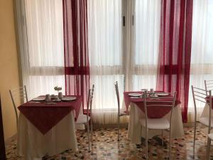 comedor con 2 mesas y cortinas rojas en B&B Myosotis, en Pisa