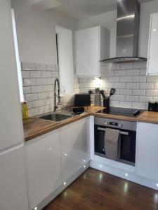 a white kitchen with a sink and a stove at Modern Apartment Nottingham in Nottingham